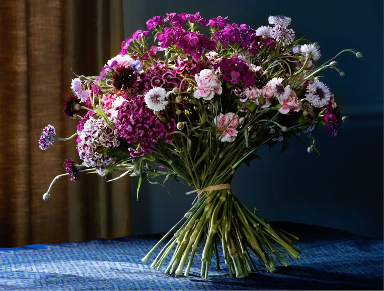 A hand-tied bouquet of purple and white carnations and scabious
