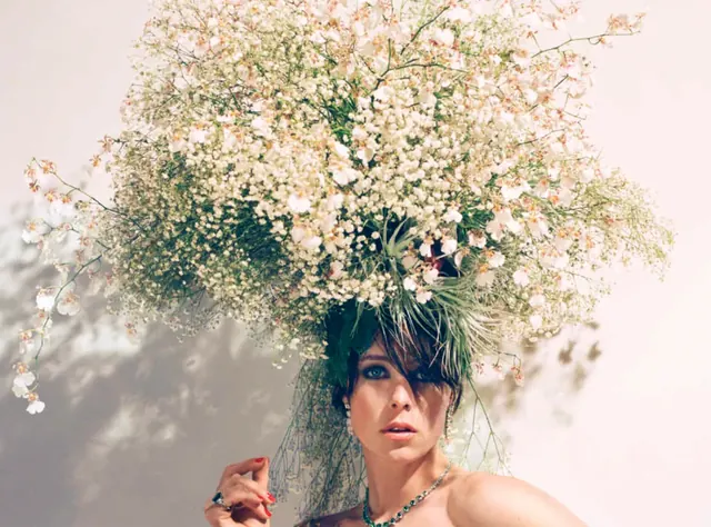 A model beneath a headpiece of delicate white flowering branches and grasses.