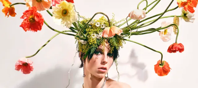 Beauty portrait of a model in a floral headpiece of coral, orange and yellow poppies for the Tiffany Botanica campaign.