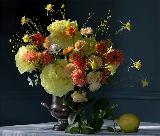Yellow dahlias, orange blooms and airy foliage in a vintage pewter vase, an editorial still life by Nina Choi for Margot.