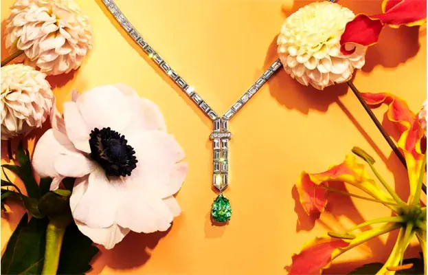 Tiffany diamond & emerald necklace against an orange ground with anemones, orchids and dahlia.