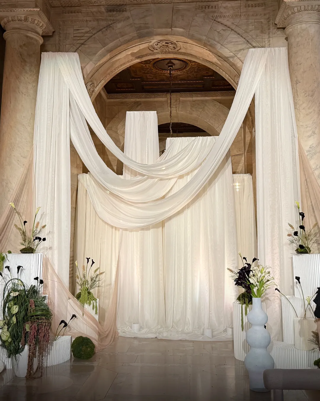 Draped ceremony installation with black and white calla lilies, composed by Buunch for a wedding at the New York Public Library