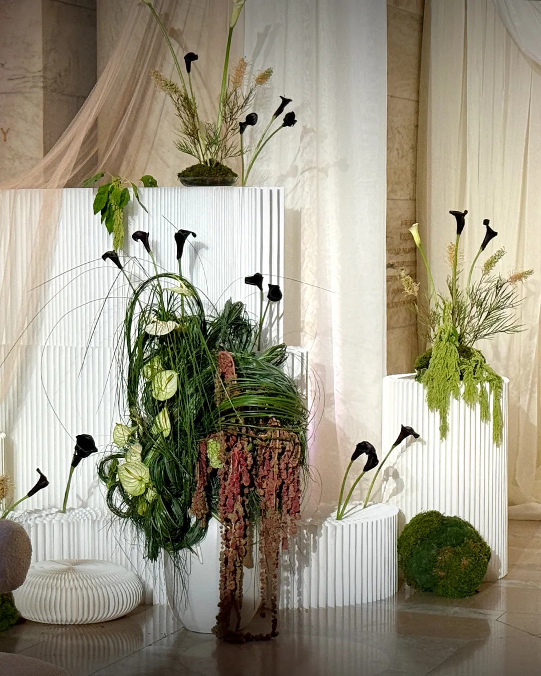 Sculptural green and white compositions on white plinths in Astor Hall, New York Public Library wedding