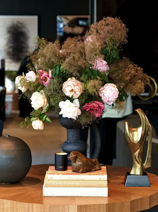 Pink and cream peonies with airy smoke bush in a black sculptural vase.
