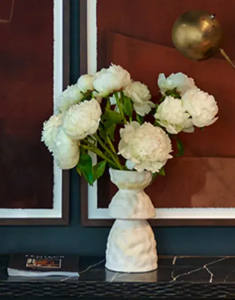 White peonies arranged in a white ceramic vase.