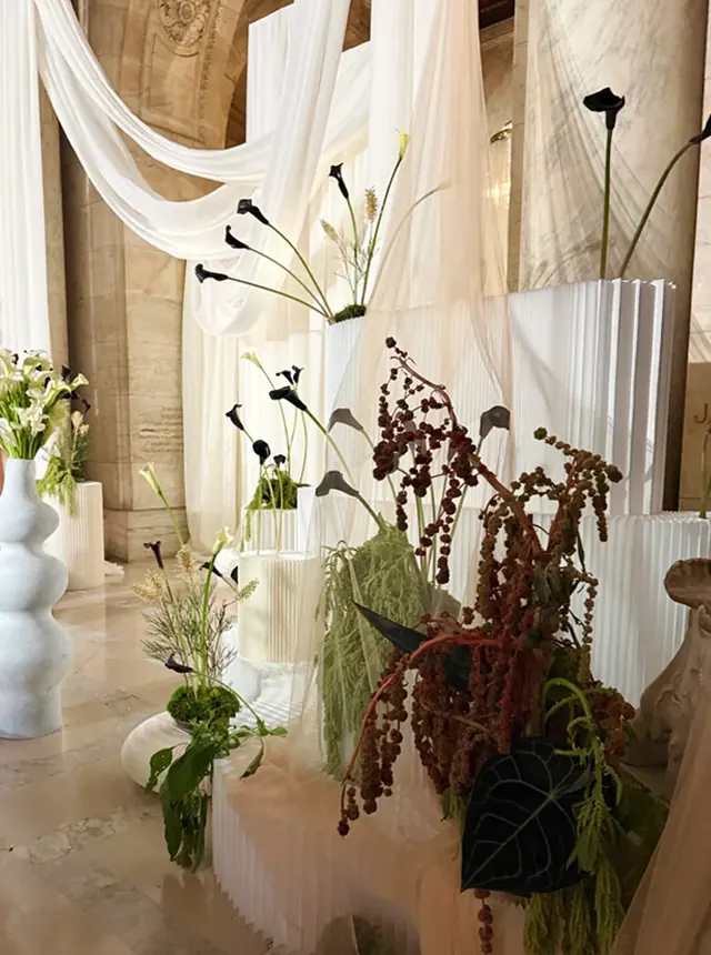 White draping, black calla lilies and sculptural vessels in a wedding installation.
