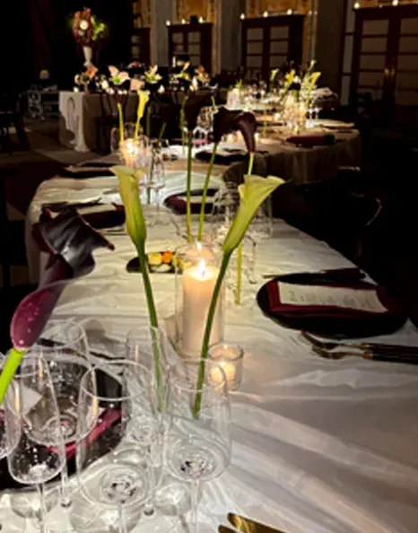 Black and pale calla lilies in individual glass vases at an autumn wedding reception at the New York Public Library.