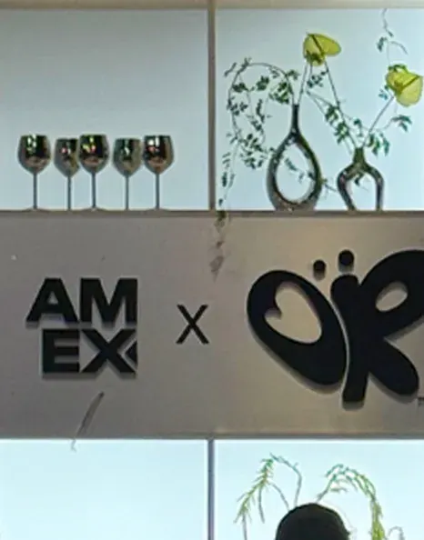 Bud vases and glassware on the American Express backdrop.