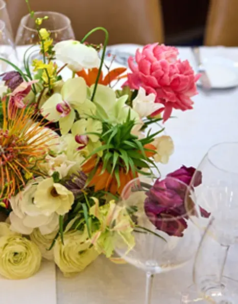 Low tablescape of pink peonies and orchids on white linen at the Tiffany & Co. shareholder dinner.