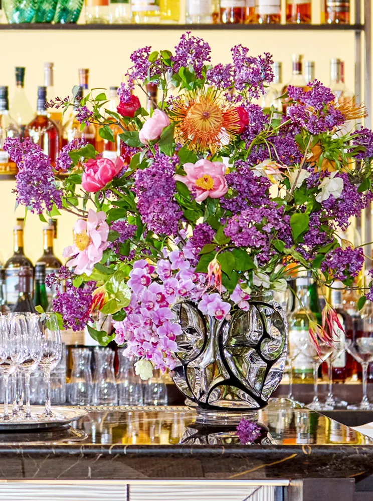 A tall floral arrangement against a bar shelf at a Tiffany & Co. shareholder dinner